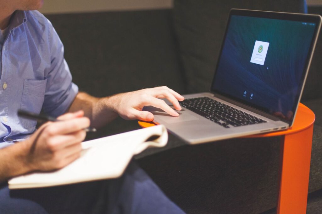 Writer working on a laptop with notes — AI writing tools