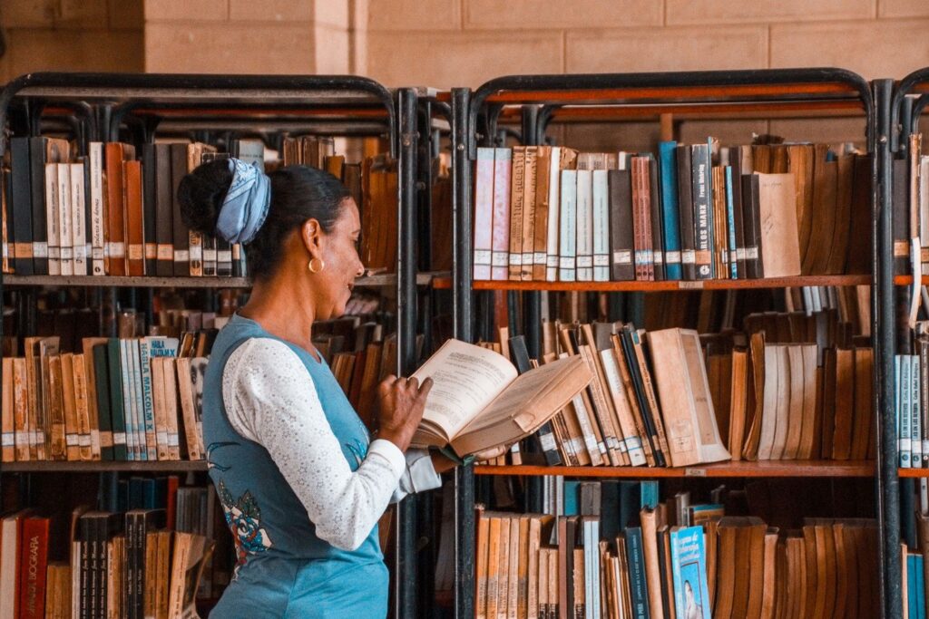 Researcher working with books and a laptop in a library, representing AI tools for academic research