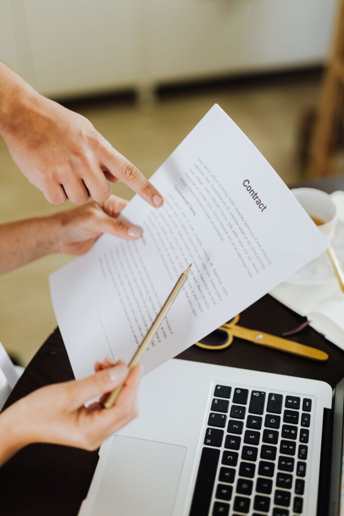 Hands reviewing printed documents next to a laptop, illustrating OCR text extraction from PDFs