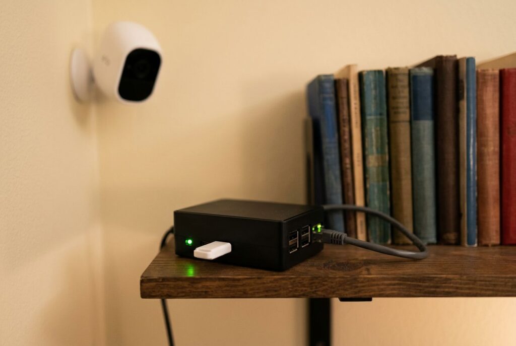Single-board computer with a USB AI accelerator stick plugged in, next to a home security camera